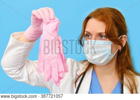 Woman Doctor Holding Pink Medical Gloves On A Blue Background, Close-up.