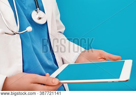 Doctor Is Looking Into A Digital Tablet, Close Up. Female Nurse In A White Coat With A Gadget In Her