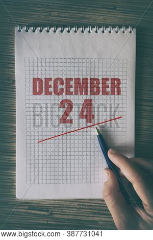 December 24th. Day 24 Of Month, Close Up Of Human Hand With Pen On Notepad With Red Underlined Date.