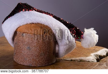 Panettone With Chocolate Chips And Santa Claus Hat On Rustic Wood With Gray Background, Selective Fo