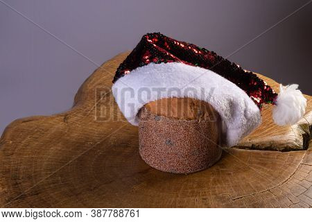 Panettone With Chocolate Chips And Santa Claus Hat On Rustic Wood With Gray Background, Selective Fo