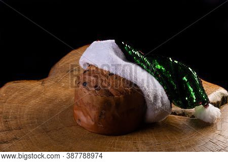 Panettone With Chocolate Chips And Santa Claus Hat On Rustic Wood With Black Background, Selective F