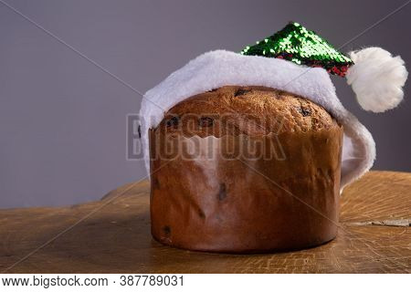 Panettone With Chocolate Chips And Santa Claus Hat On Rustic Wood With Gray Background, Selective Fo