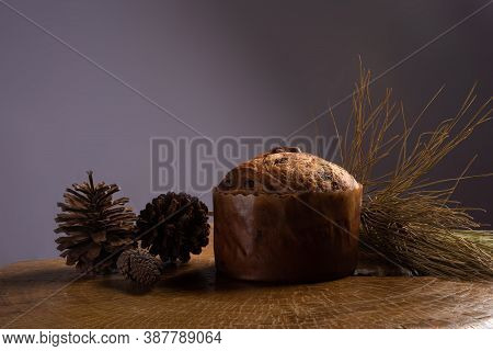 Panettone With Chocolate Chips On Rustic Wood With Pine Cones And Branches With Gray Background, Sel