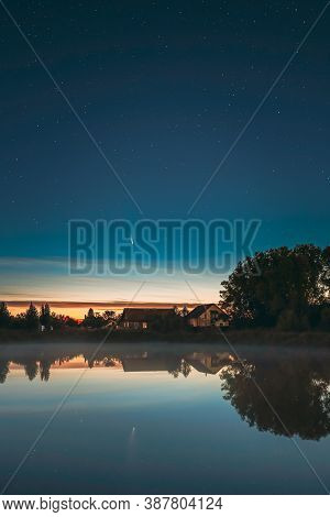 Dobrush, Belarus. Comet Neowise C2020f3 In Night Starry Sky Reflected In Small Lake Waters