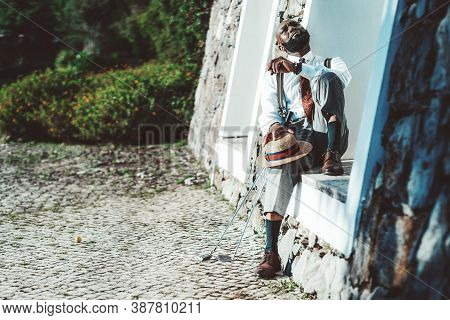 A Fancy Mature Bearded Black Man With A Hat In His Hand And A Cigar In Another Hand Is Having Rest A