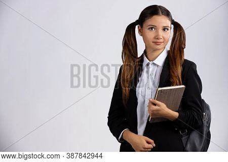 Beautiful Young Brunette Woman With Long Hair And Big Eyes Looking At Camera, Holding Book In Her Ha