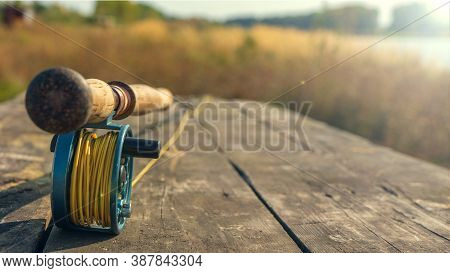 Fly Fishing Rod With On Wood Background. Autumn Sunny Day. Autumn Sunny Day.