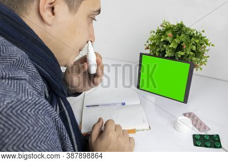 The Sick Man Looks At The Tablet. The Gadget Has A Green Screen Instead Of A Monitor. The Concept Of