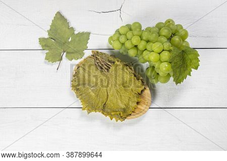 Grape Vine Leaf In Bowl With Fresh Grape Fruit On Rustic Background, Turkish Pickled Leaf Grows In T