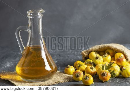 Glass Bottle Of Hawthorn Vinegar With Fresh Ripe Red/yellow Hawthorn Fruits On Rustic Background. Cr