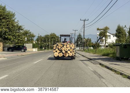 Harvesting Firewood. Tractor Transports Huge Tree Trunks Along A Rural Street (greece)