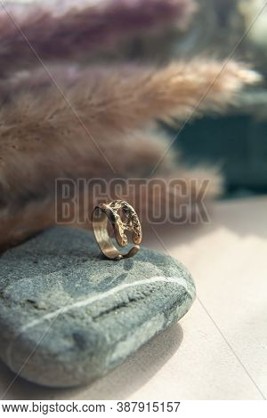 Trendy Vintage Cast Brass Ring. Jewelry Womens Ring Abstract Drawing Closeup On A Gray Natural Stone