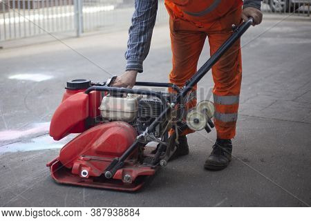Asphalt Rammer. Laying The Road Surface. Creation Of Parking. The Worker Levels The Road Surface. Ho