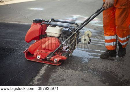 Asphalt Rammer. Laying The Road Surface. Creation Of Parking. The Worker Levels The Road Surface. Ho
