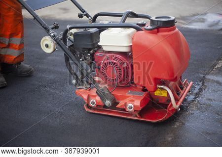 Asphalt Rammer. Laying The Road Surface. Creation Of Parking. The Worker Levels The Road Surface. Ho