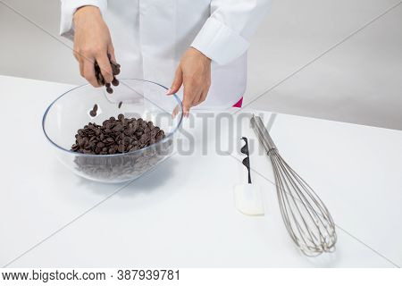 Closeup Female Chef Pours Dark Chocolate Drops Chips Morsels Callets Isolated On White Background. C