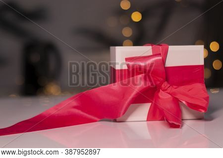 White Gift Box With Pink Ribbon Bow On Gold Bokeh Background