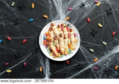Halloween Tasty Cookies In Form Of Witches Fingers And Colorful Candies On Black Background With Spi