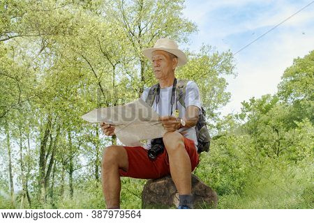 Concept Of Eco-friendly Tourism : Elderly Man In Ecotourism Sat Looking At The Map To Study The Natu
