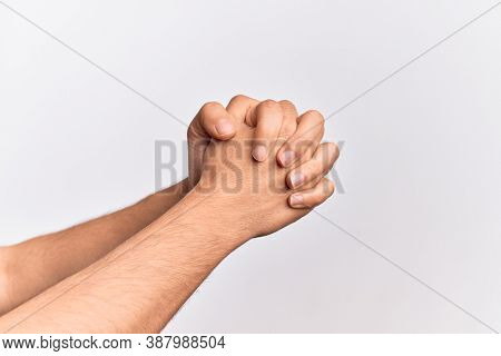 Hand of caucasian young man showing fingers over isolated white background praying with hands clasped, fold fingers religious gesture