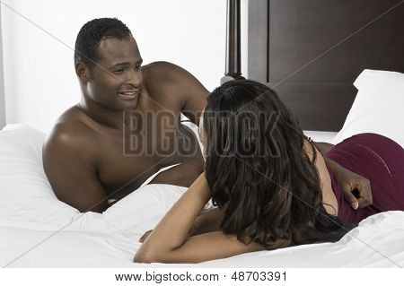 Uśmiechnięty mężczyzna African American, patrząc na kobietę w łóżku