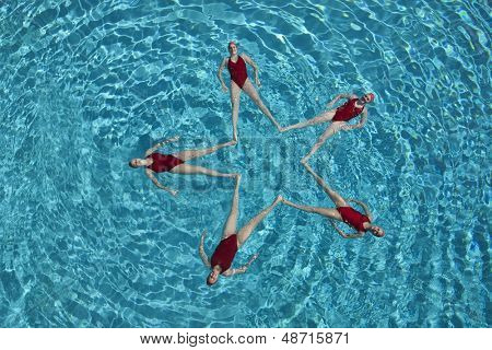 Vista elevada de nadadores sincronizados formando una forma de estrella en la piscina