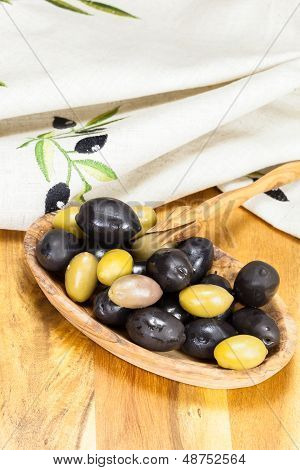 Olives in olive wood bowl with olive picker