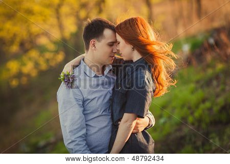 couple kissing standing outdoos among bushes