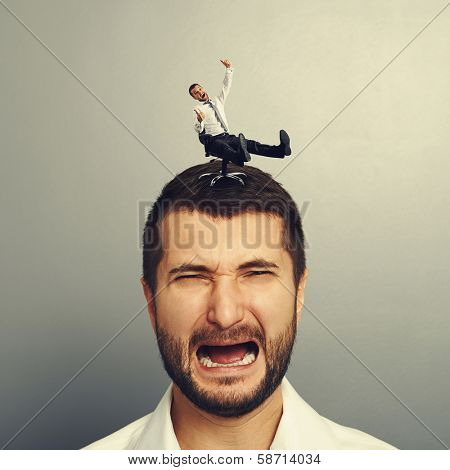 portrait of sad screaming man with small happy man on the head