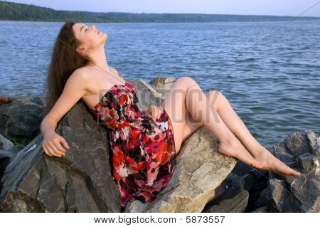 Girl sit on rock on sea coast