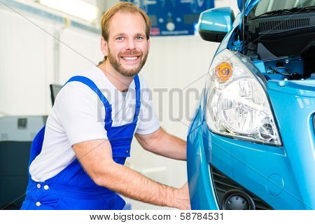 Mechanic in workshop or MOT with car or auto for service inspection
