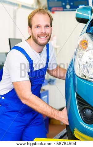 Mechanic in workshop or MOT with car or auto for service inspection