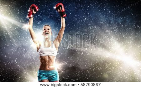 Young pretty boxer woman standing in light flashes