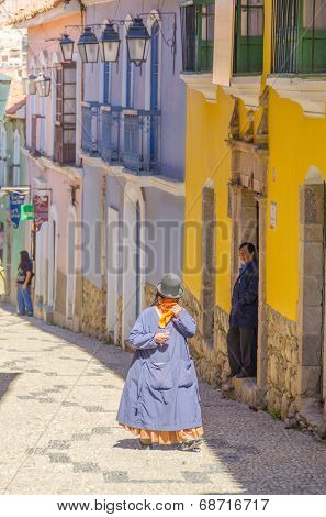 LA PAZ, BOLIVIA, MAY 8, 2014 - Local woman in traditional costume and bowler hat walks down the street Calle Jaen near museums complex