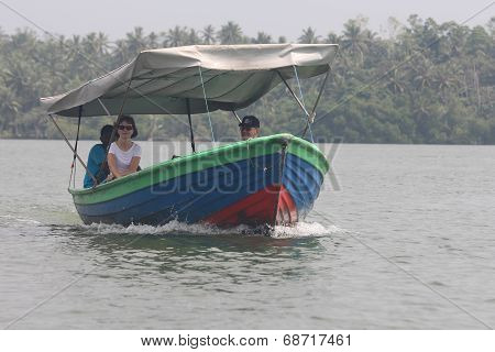 Tourists walking by the boat down the Bentota river.