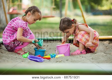 Two girls play in the sandbox