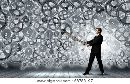 Young businessman fixing gears mechanism with wrench