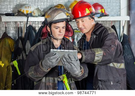 Male firefighters discussing over digital tablet at fire station