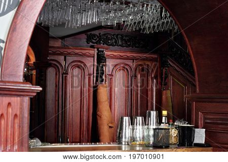 Classic Bar Counter With Bartender Accessories Shakers With Leather Apron Of Bartender Hanging On Wo