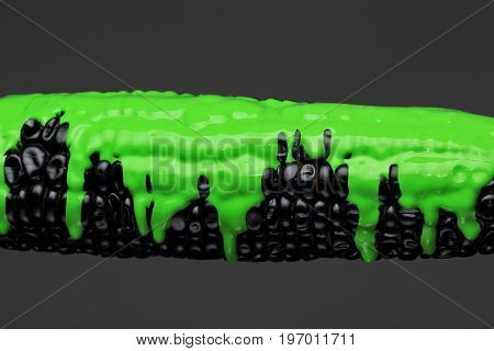 Black corn with pouring green paint background, macro closeup.Texture