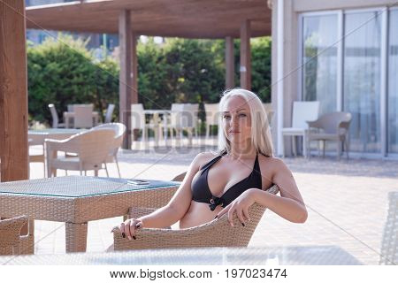blonde girl sitting at the beach restaurant