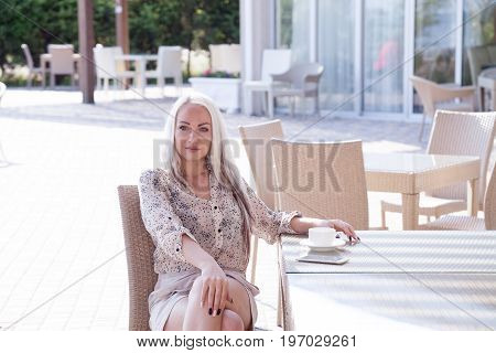 blonde girl sitting at the beach restaurant coffee drinkers
