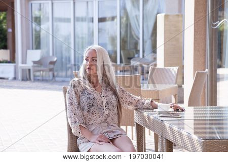 blonde girl sitting at the beach restaurant coffee drinkers