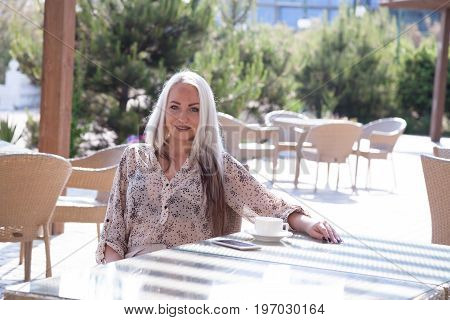blonde girl sitting at the beach restaurant coffee drinkers