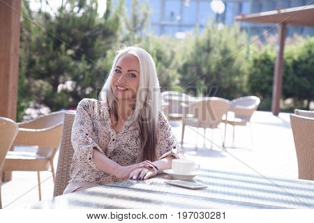 blonde girl sitting at the beach restaurant coffee drinkers