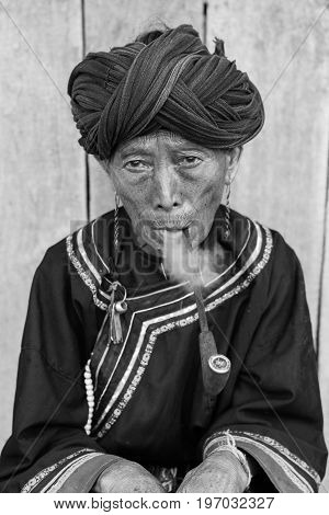 Phongsali Privince Laos - 25.July 2010: senior adult hill tribe woman in traditional clothes smoke her pipe
