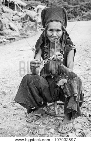 Phongsali Privince Laos - 24.July 2010: senior adult hill tribe woman in traditional clothes smoke her pipe