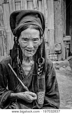 Phongsali Privince Laos - 24.July 2010: senior adult hill tribe woman in traditional clothes smoke her pipe