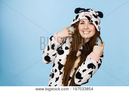 Happy teenage girl in funny nightclothes pajamas cartoon style smiling positive face expression studio shot on blue.